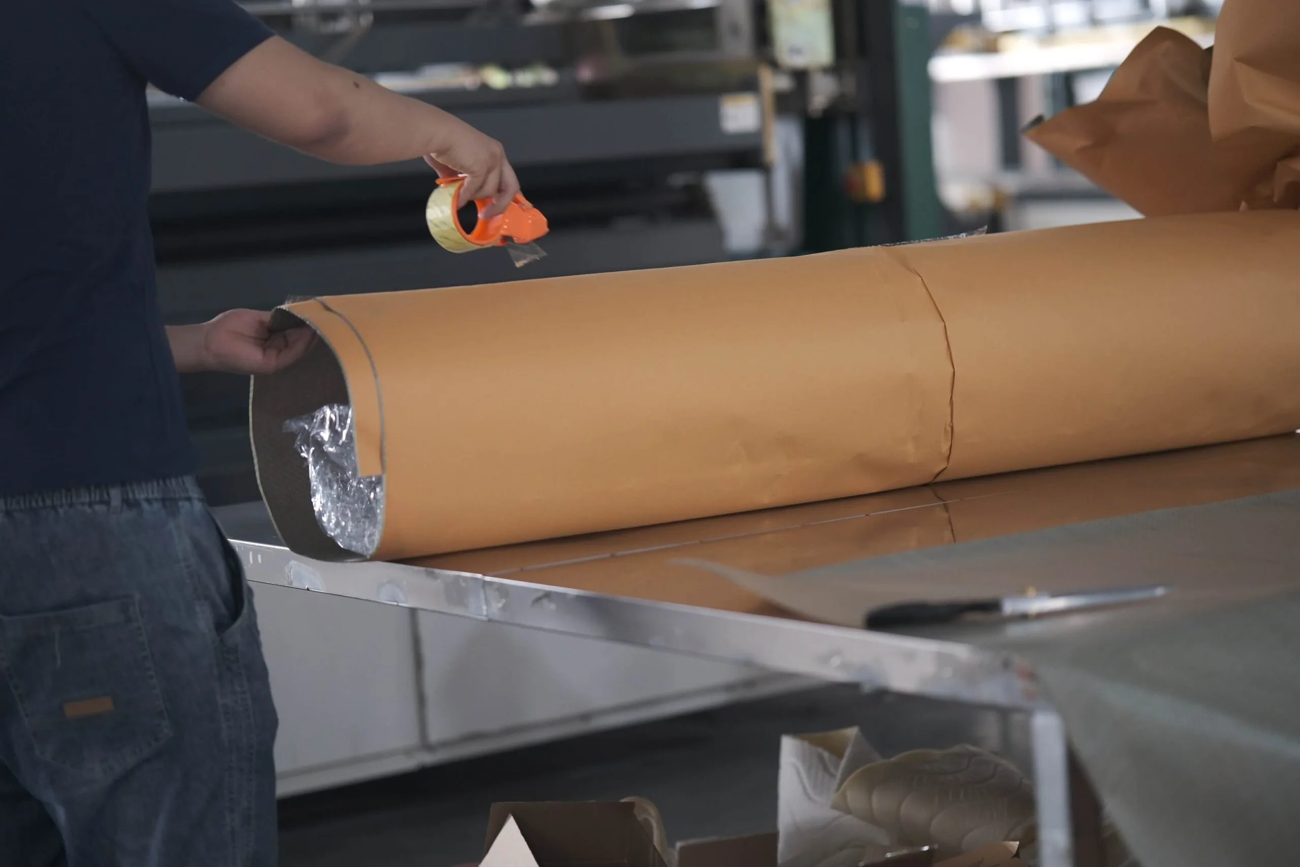 Worker packaging a rolled-up mattress for shipping in a compact box