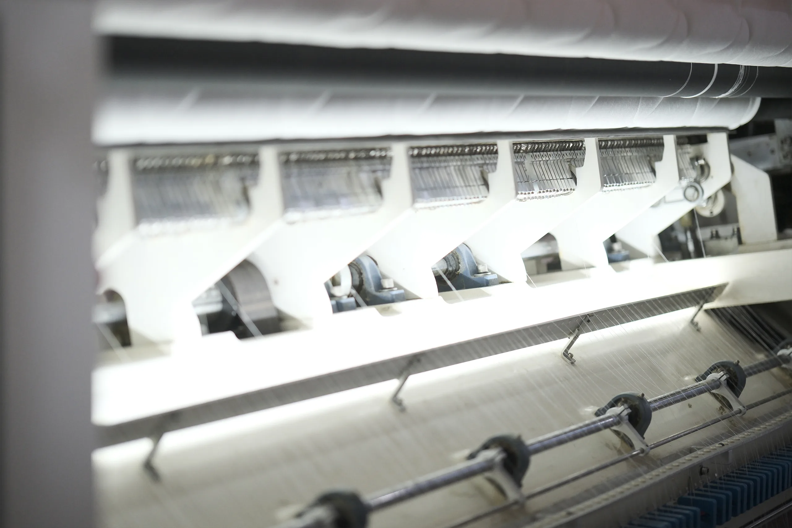Close-up of quilting machine stitching fabric during mattress production in factory