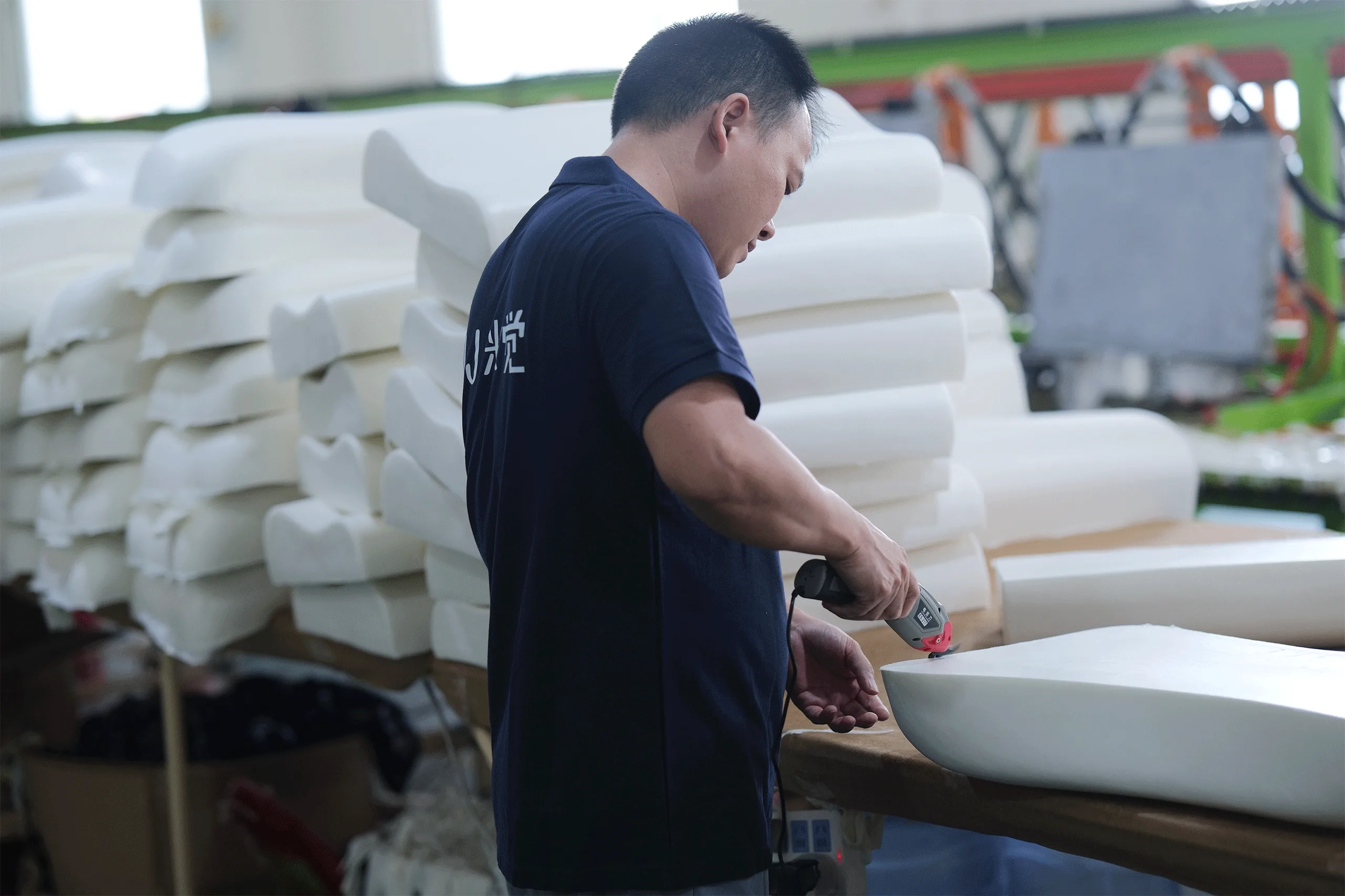Worker trimming the edges of a newly molded pillow