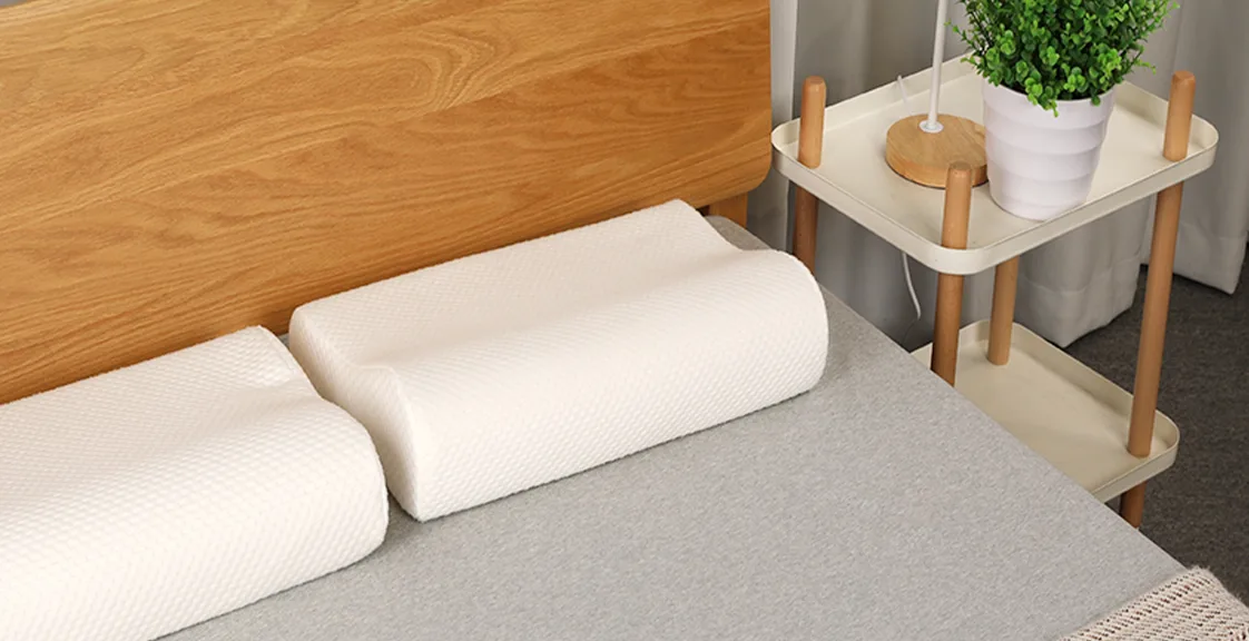 Two memory foam pillows placed on a neatly made bed near a wooden headboard, illustrating how to dry a memory foam pillow in a well-ventilated room