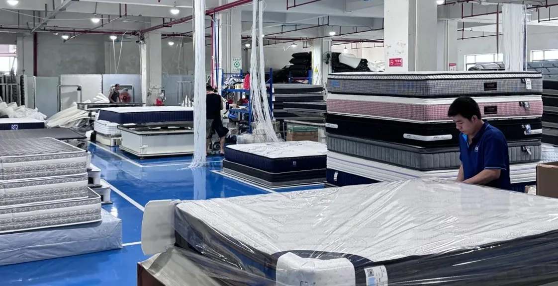 Workers packing mattresses in factory