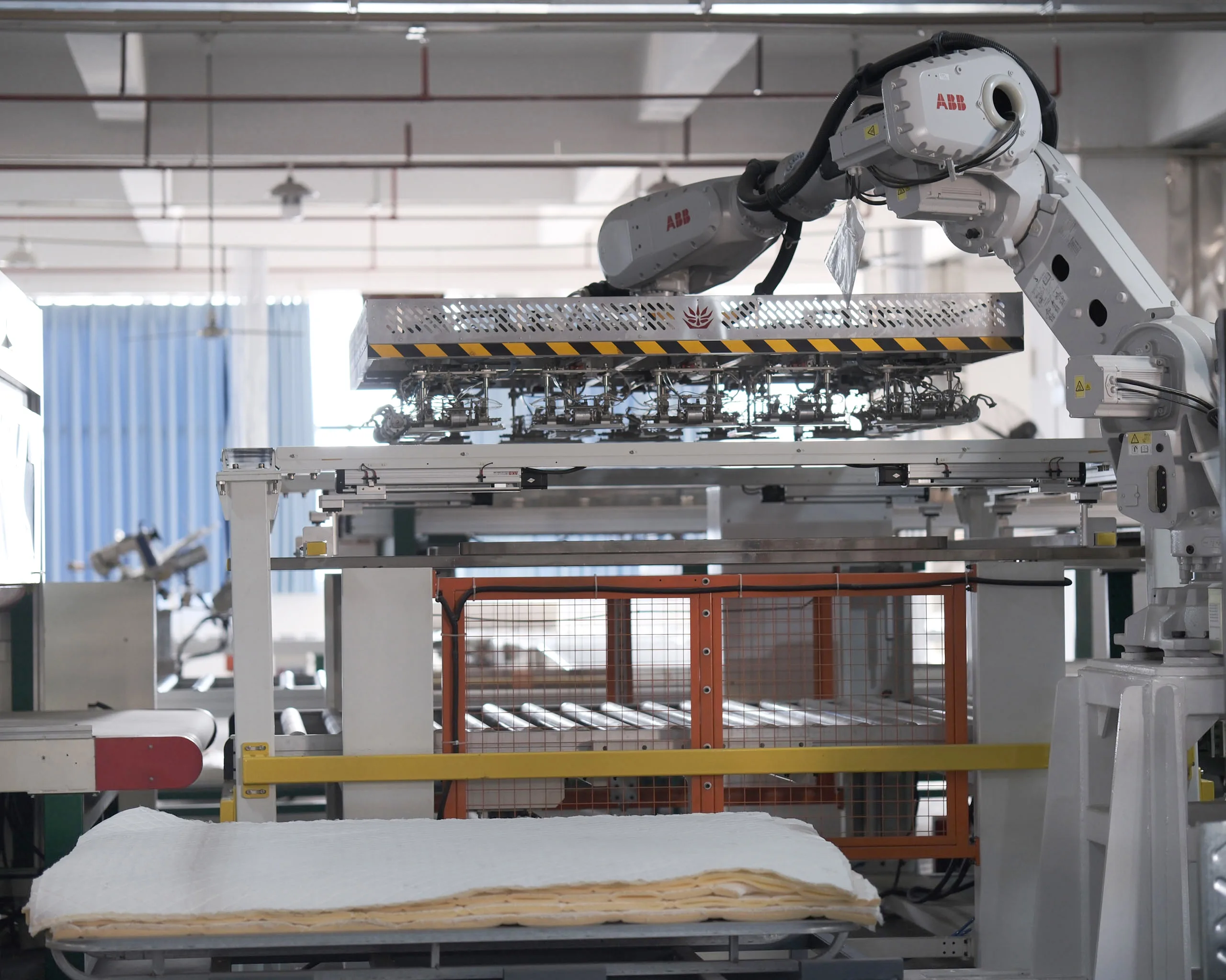Automated machine assembling mattress layers in factory, improving production efficiency and ensuring consistent quality