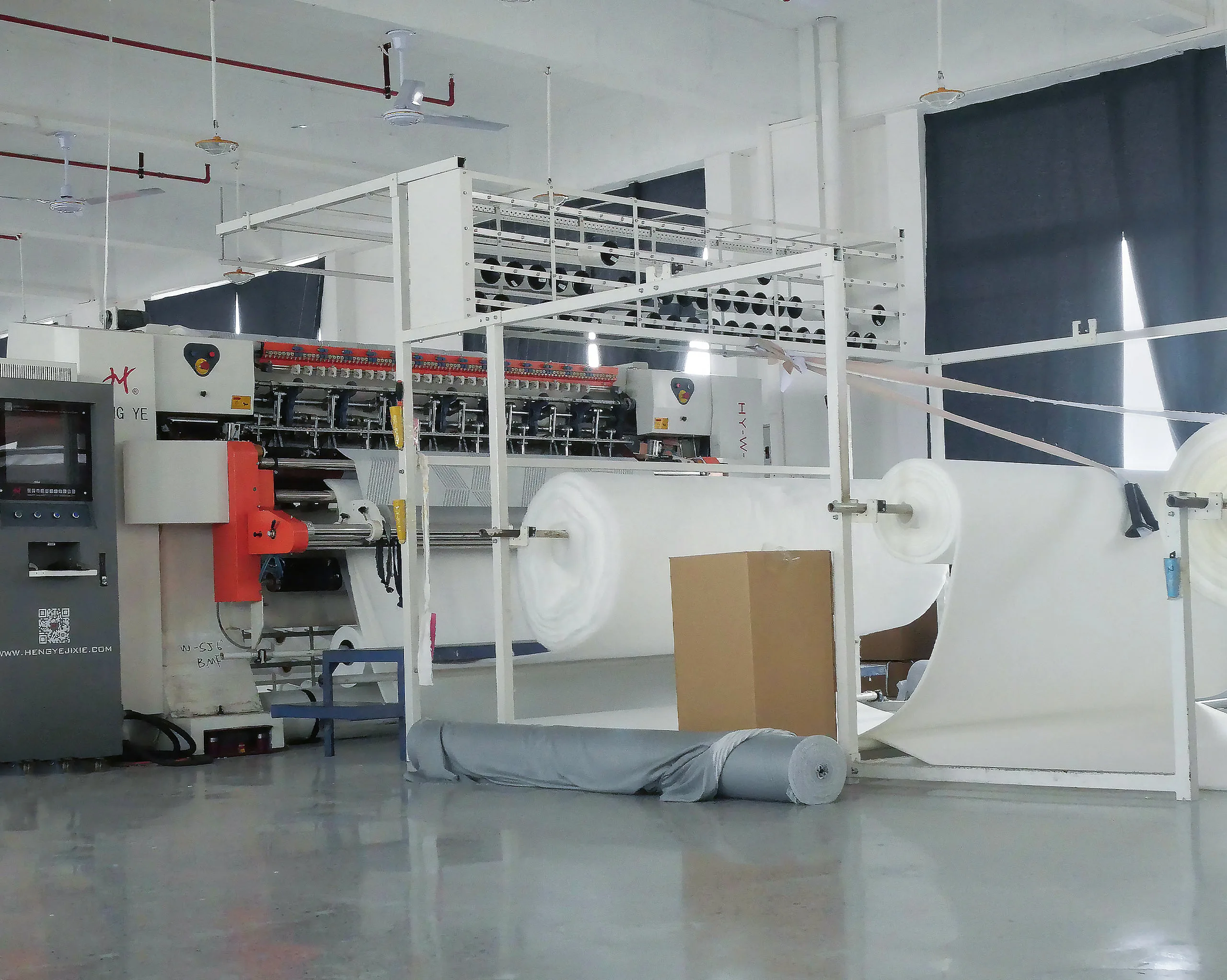 Automated quilting production line processing large rolls of padding material, demonstrating efficient and large-scale mattress fabric manufacturing capability
