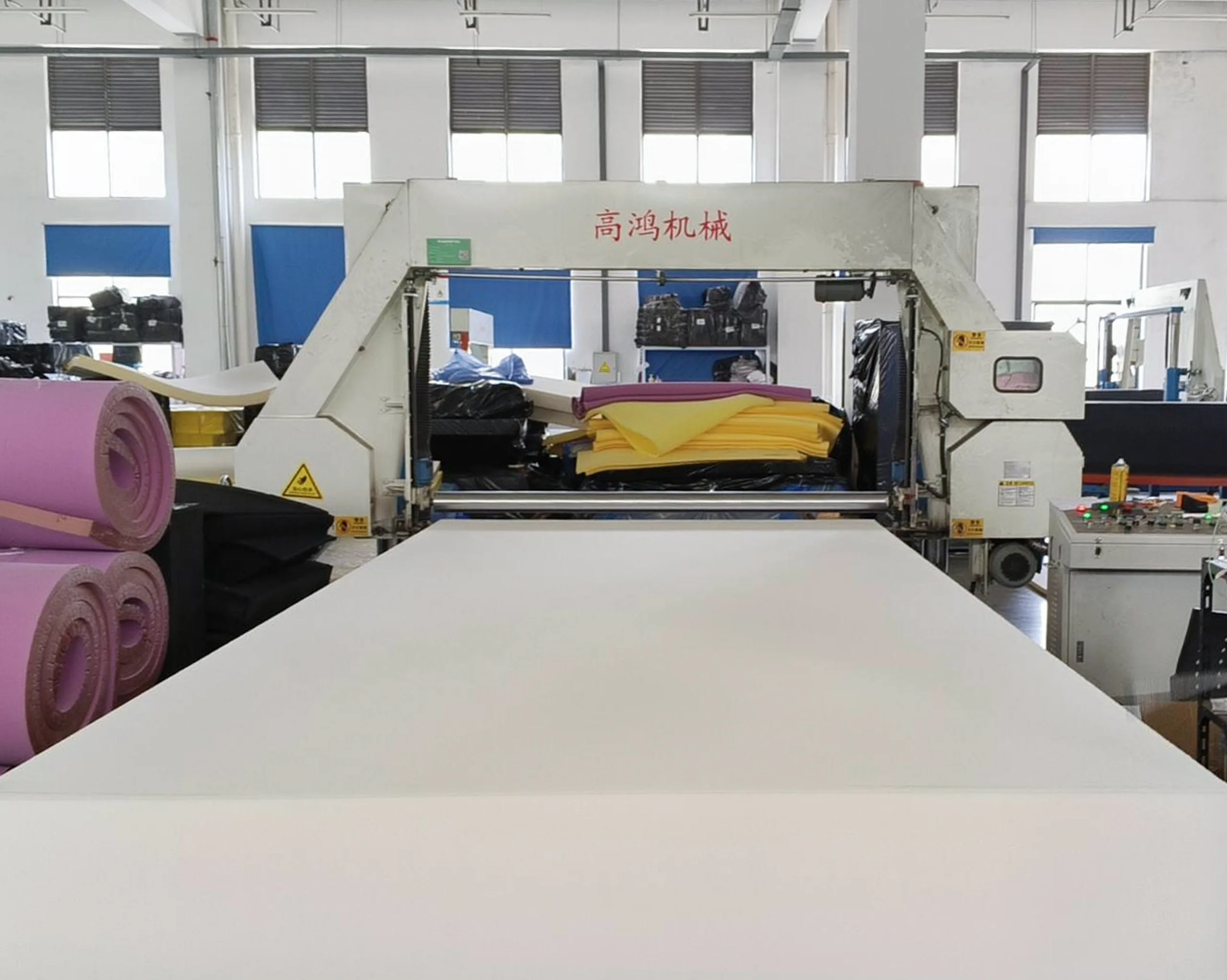 Automated machine performing horizontal cutting and shaping of multi-layer foam materials, suitable for various densities and colors, demonstrating flexible and efficient production capability