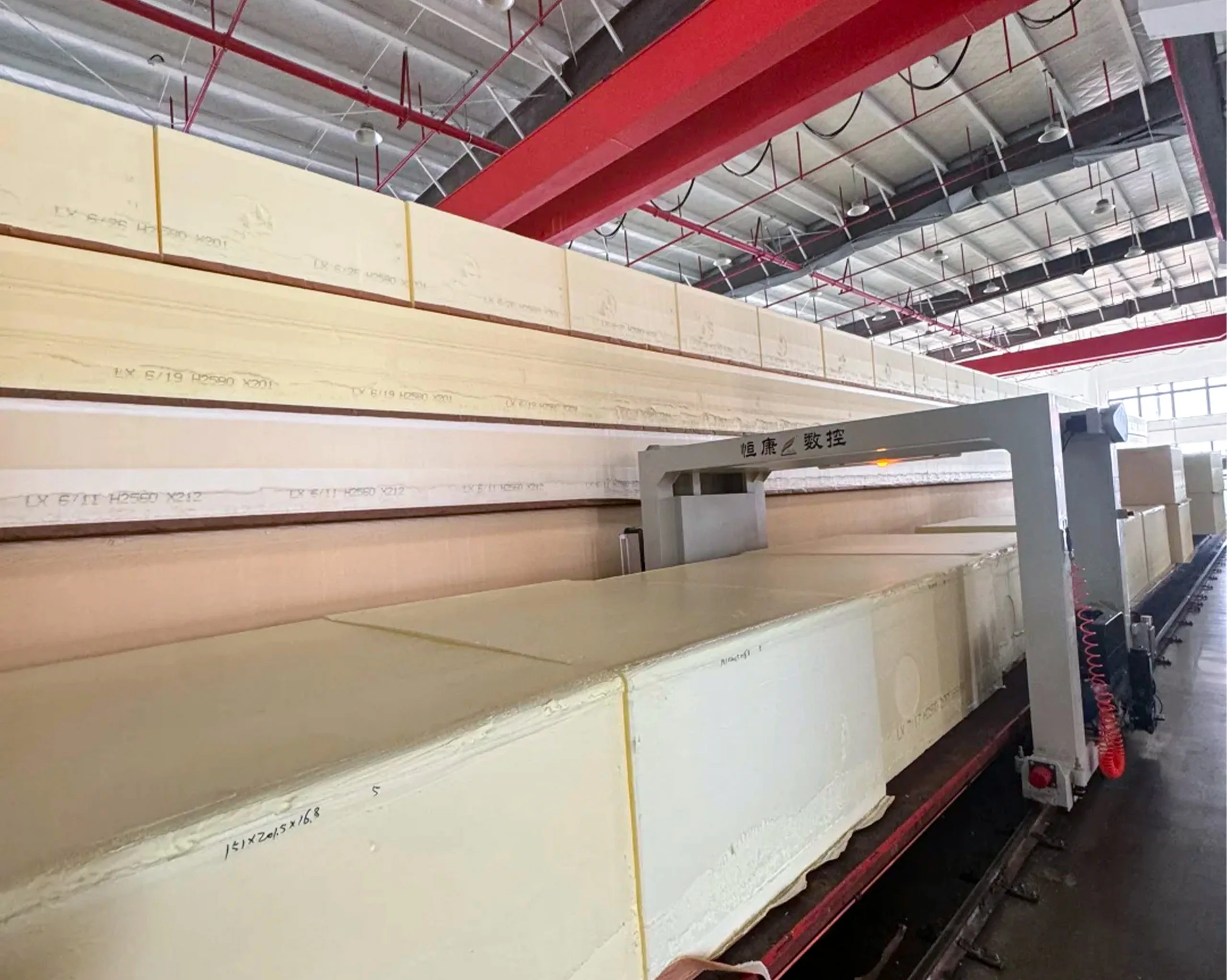 Large foam blocks being precisely cut by automated cutting machine into different sizes for mattress production, demonstrating efficient material processing capability